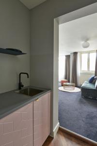 a kitchen with a sink and a living room at Hotel Pistache Den Haag in The Hague