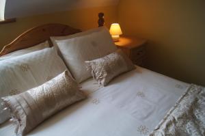 1 dormitorio con 1 cama con sábanas y almohadas blancas en Southwind B&B, en Spanish Point
