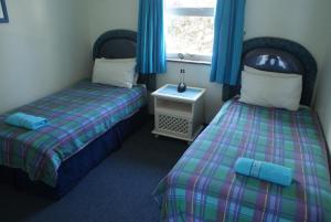 a room with two beds and a window with blue curtains at Rosscarbery 2 in Margate