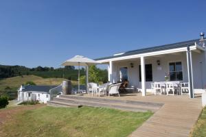 
a white house with a patio with a white table and chairs at Paul Wallace Wines & Cottages in Elgin
