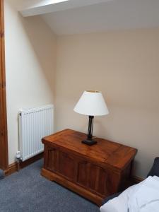 a lamp on a wooden table in a bedroom at Church View at Plover Cottage Lindley in Huddersfield