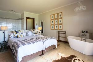 a bedroom with a large bed and a bath tub at Buhala Lodge in Malelane