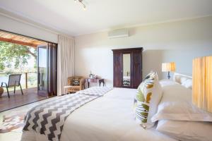 a bedroom with a large bed and a balcony at Buhala Lodge in Malelane