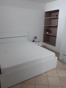 uma cama branca num quarto branco com uma prateleira em Barco Apartment em Ostuni