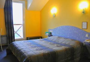 sypialnia z niebieskim łóżkiem i oknem w obiekcie Logis Argonne Hôtel w mieście Vouziers