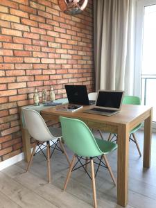 グダニスクにあるBastion wałowa - luxury apartment with beautiful viewの木製テーブル(椅子付)に座ったノートパソコン2台