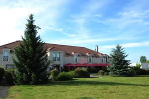 um grande edifício branco com árvores no quintal em Logis Argonne Hôtel em Vouziers