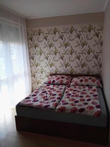 1 dormitorio con 1 cama y papel pintado con motivos florales en Kiskuckó Apartman en Hajdúszoboszló