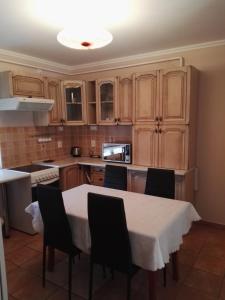 a kitchen with a table with chairs and a white table cloth at Kiskuckó Apartman in Hajdúszoboszló