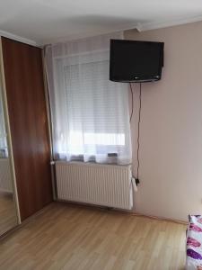 a room with a window with a television on a wall at Kiskuckó Apartman in Hajdúszoboszló