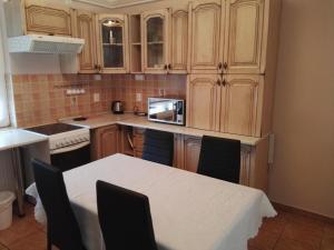una cocina con armarios de madera y una mesa blanca con sillas. en Kiskuckó Apartman en Hajdúszoboszló