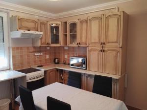 una pequeña cocina con armarios de madera y una mesa. en Kiskuckó Apartman en Hajdúszoboszló