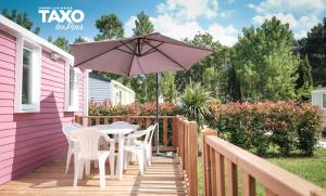 een patio met een tafel en stoelen en een parasol bij Camping Taxo Les Pins in Argelès-sur-Mer