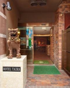 una taza de hotel con una estatua delante de un edificio en Hotel Taira, en Naha