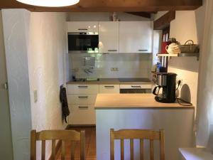 una cucina con armadi bianchi e un bancone con due sedie di Cosy and snug holiday home with joint swimming pool a Zichemsveld
