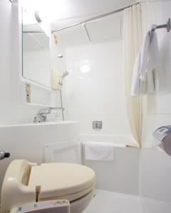 een witte badkamer met een toilet en een wastafel bij Hotel Taira in Naha