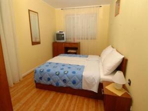 a small bedroom with a bed and a television at Pansion Sport in Štinjan