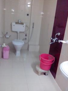 a bathroom with a toilet and a red bucket at Hotel Mohit in Darjeeling
