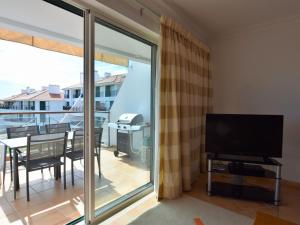 uma sala de estar com uma televisão e uma varanda em Spacious Apartment in Quarteira with Swimming Pool em Vilamoura