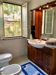 a bathroom with a sink and a toilet and a window at Villetta Dei Glicini in Santa Caterina
