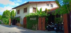 a white house with a red fence and some motorcycles at Seven Senses Guesthouse in Chiang Mai