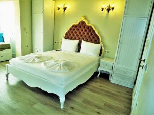 a bedroom with a large white bed with a large headboard at Grand Alaçatı Butik Hotel in Alaçatı