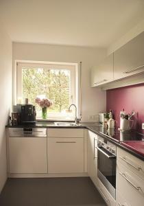 a kitchen with white cabinets and a window and a sink at seeglueck SONNENSCHEIN uninahes Appartment mit sonnigem Südbalkon und eigenem Tiefgaragenstellplatz in Konstanz
