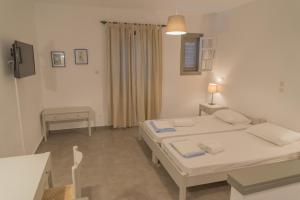 a room with two beds and a table and a desk at Ostria Hotel & Apartments in Gavrio