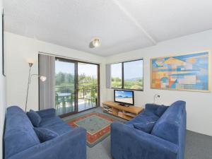 a living room with two blue couches and a television at Foreshore Paradise Nelson Bay in Nelson Bay