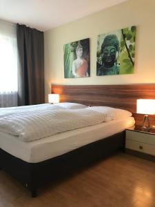 a bedroom with a bed with two lamps and portraits on the wall at Apartmenthaus Sonnen in Düsseldorf