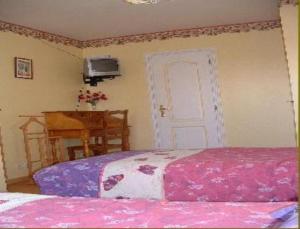 a bedroom with two beds and a table and a door at La Vallée des Trois Monts in Saint-Sylvestre-Cappel