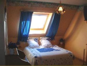 1 dormitorio con 1 cama con cortinas azules y ventana en La Vallée des Trois Monts en Saint-Sylvestre-Cappel