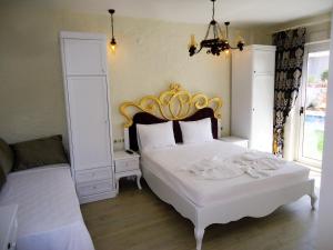 a bedroom with a white bed with a gold headboard at Grand Alaçatı Butik Hotel in Alaçatı
