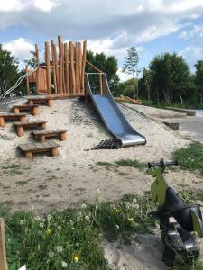 einen Spielplatz mit Rutsche im Sand in der Unterkunft Sdr. Bork in Hemmet