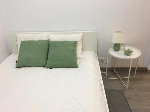 uma cama branca com almofadas verdes e uma mesa lateral em New Luxury Apartment - Lisbon Center em Lisboa