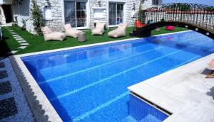 a blue swimming pool with chairs and a bridge at Grand Alaçatı Butik Hotel in Alaçatı