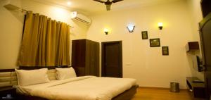 a bedroom with a bed with white sheets and a window at La Bellevue (Club & Resort) in Rāmnagar