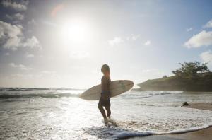 MiramarにあるSentidos Beach Retreatの浜辺に立ちサーフボードを持つ男