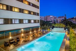 - une piscine sur le côté d'un bâtiment dans l'établissement Enea Hotel Pomezia, à Pomezia