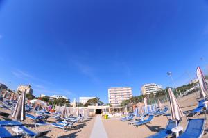 Hotel Antares في ميكيلي: مجموعة من الكراسي والمظلات على الشاطئ