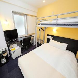 a bedroom with a bed and a desk and bunk beds at Super Hotel JR Shin-Osaka Higashiguchi in Osaka