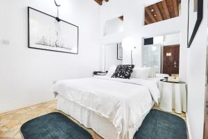 a white bedroom with a bed and two rugs at XVA Art Hotel in Dubai