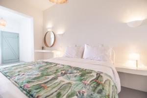 Dormitorio blanco con cama con manta en Agave Santorini Design Boutique Hotel, en Imerovigli