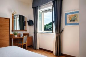 een slaapkamer met een bed, een raam en een bureau bij Casa Ferretti di Ferretti Village in Silvi Marina