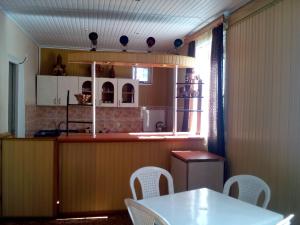 una cucina con tavolo, sedie bianche e bancone di Guest House Giorgi a Ureki