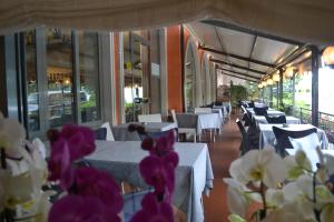 a restaurant with white tables and chairs and purple flowers at Hotel Smeraldo in Brenzone sul Garda
