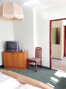 een kamer met een tv, een stoel en een spiegel bij Hotel Garni in Bad Schallerbach