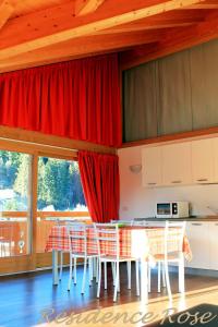 a kitchen with a table and some red curtains at Residence Rose in Valdisotto