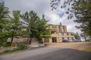 un grand bâtiment avec des arbres devant lui dans l'établissement Hotel Gorropu, à Urzulei