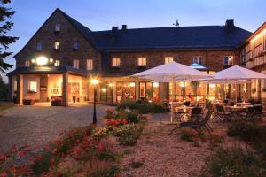 ein Gebäude mit Tischen und Sonnenschirmen davor in der Unterkunft Sonnenhotel Hoher Hahn in Schwarzenberg